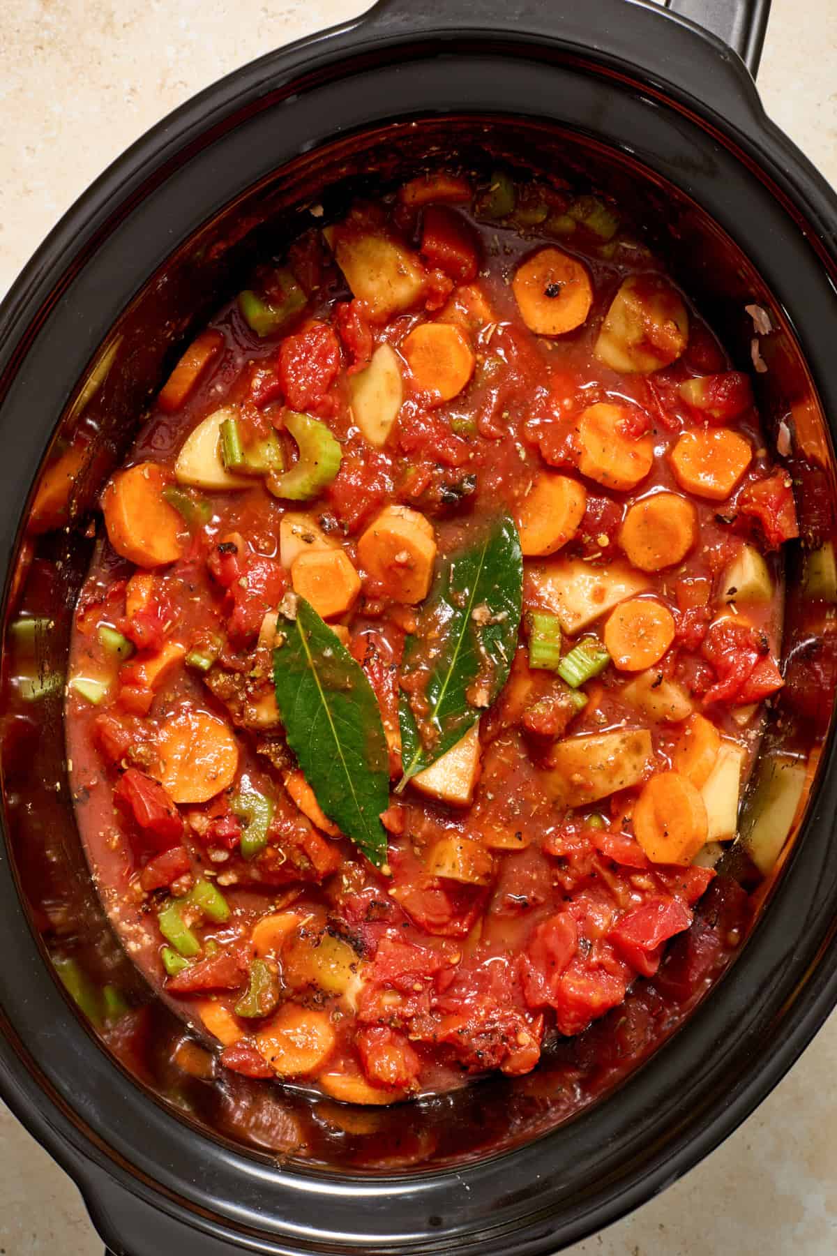 Carrots, potatoes, celery and other ingredients combined in slow cooker.