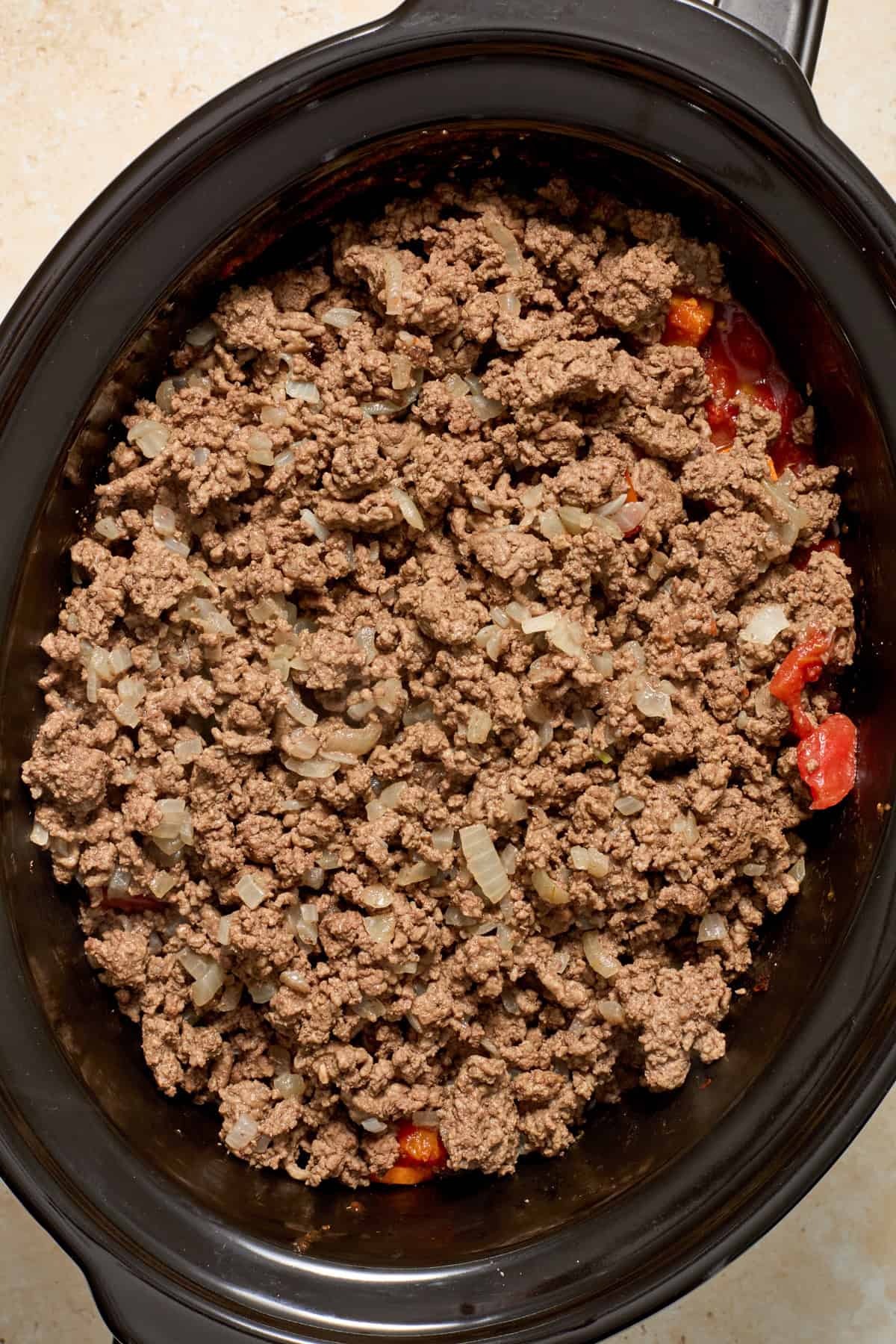 Browned ground beef and onions added to crockpot.