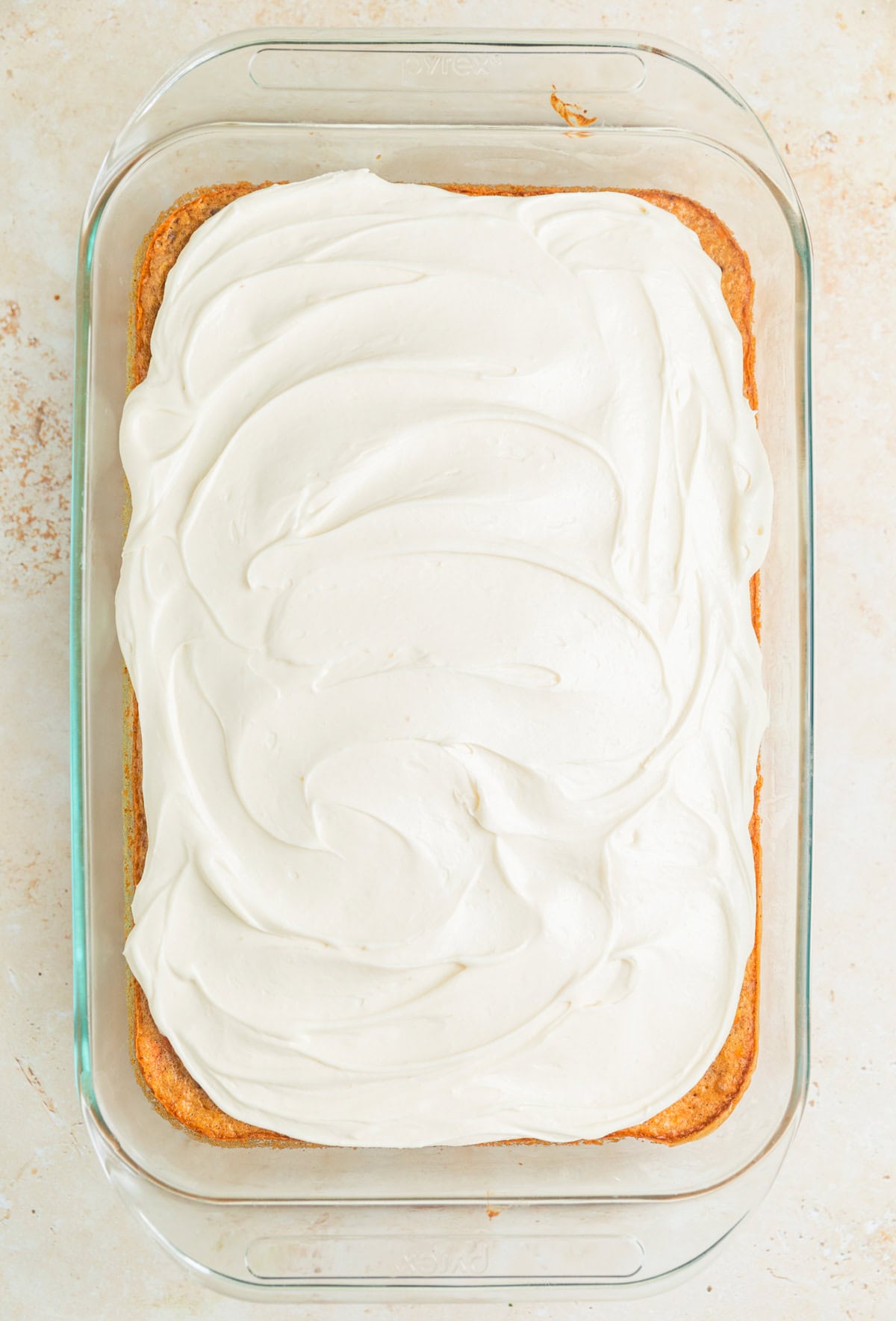 Iced carrot sheet cake in cake pan.