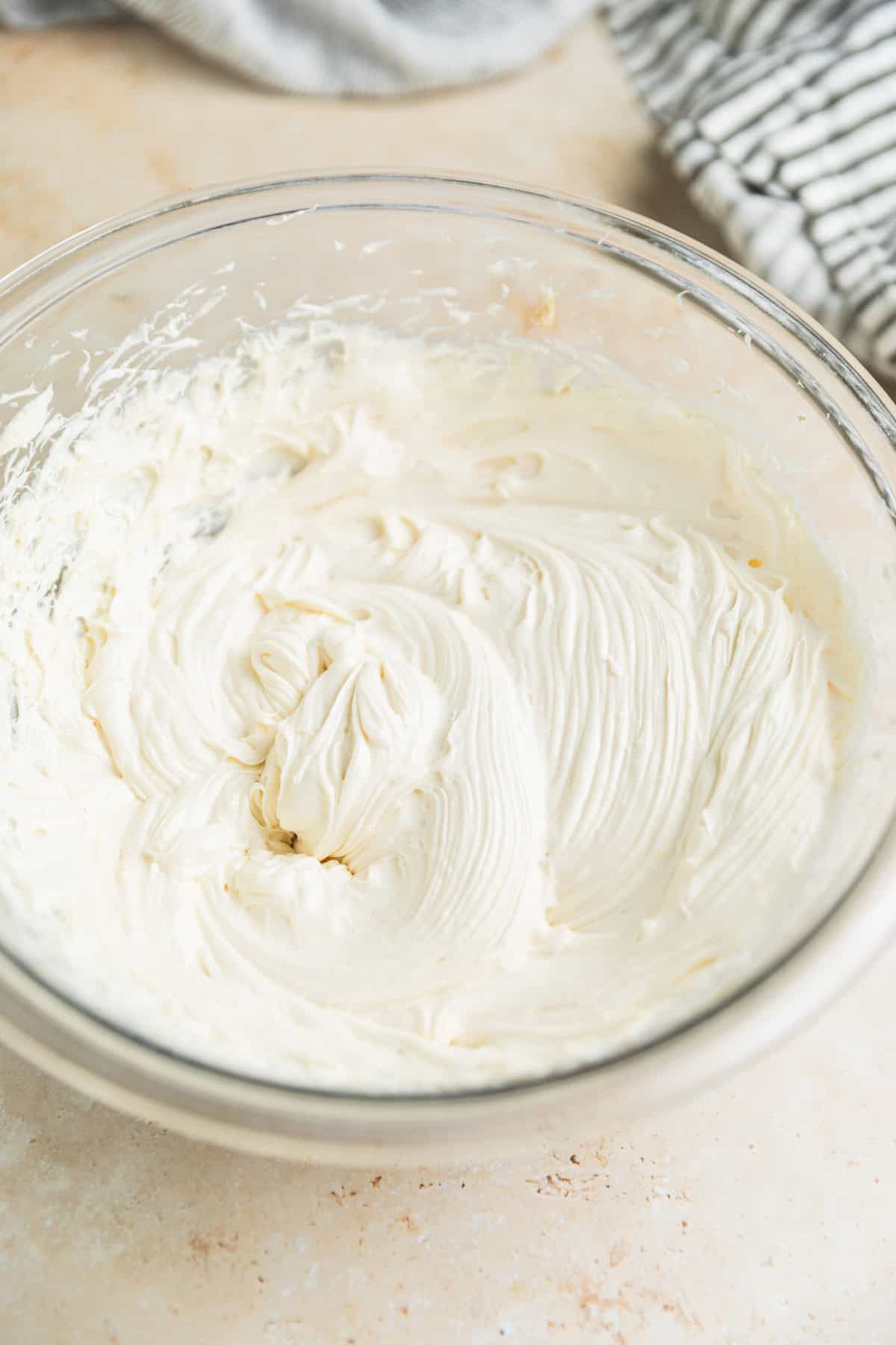 Cream cheese frosting whipped with cream cheese in glass bowl.