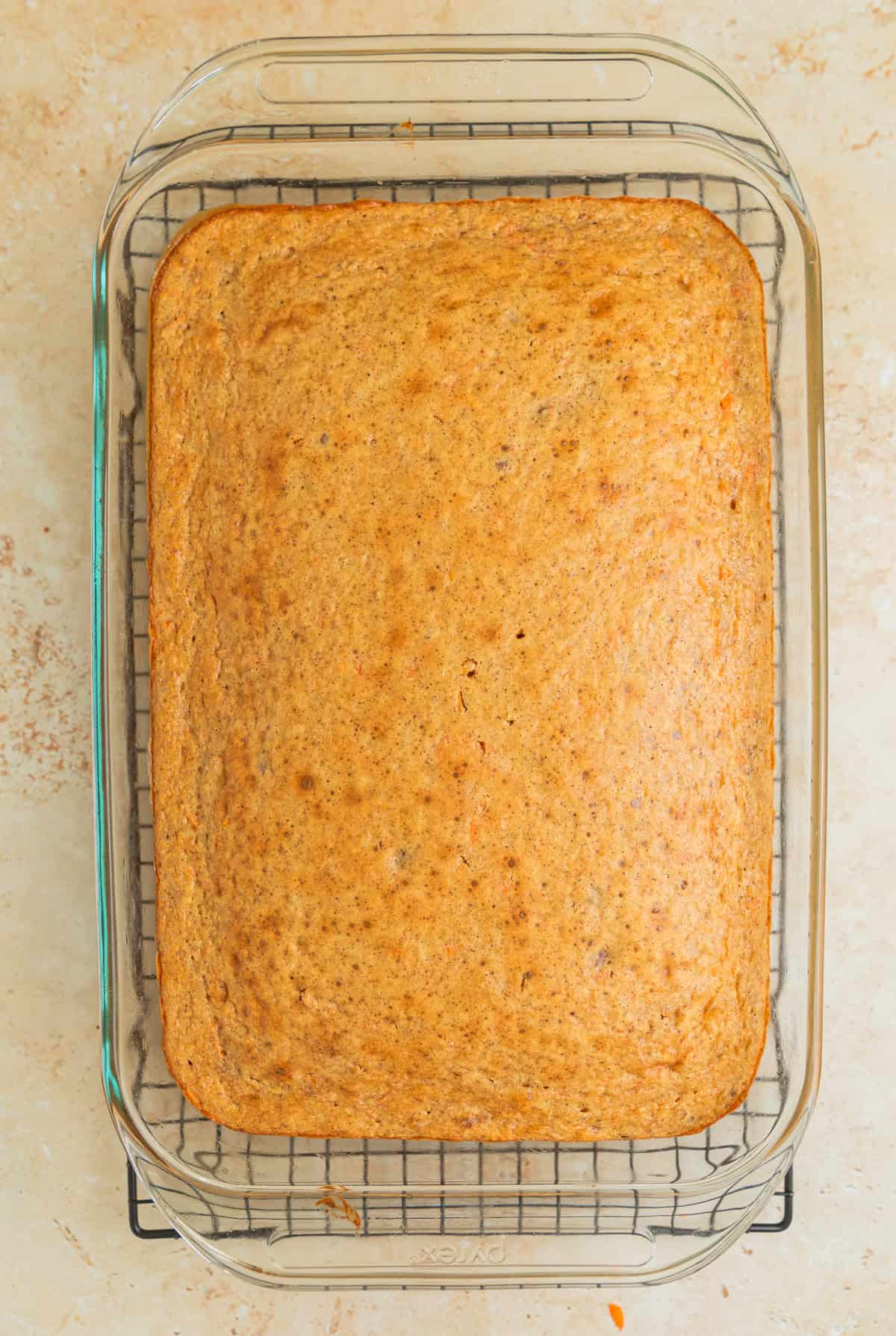 Carrot cake baked in pan on cooling rack.