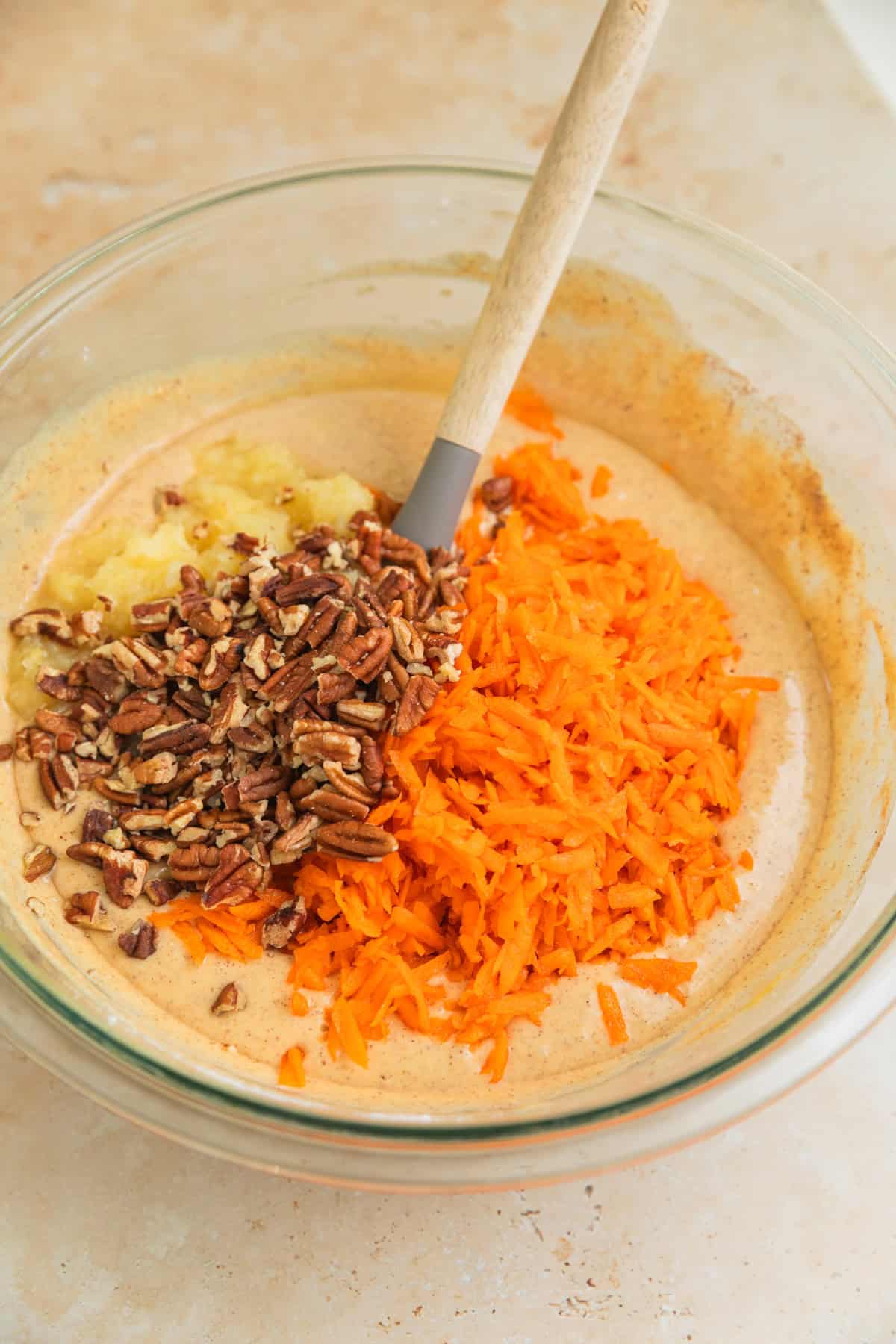 Shredded carrots, pecans and pineapple in bowl of cake batter before stirring.