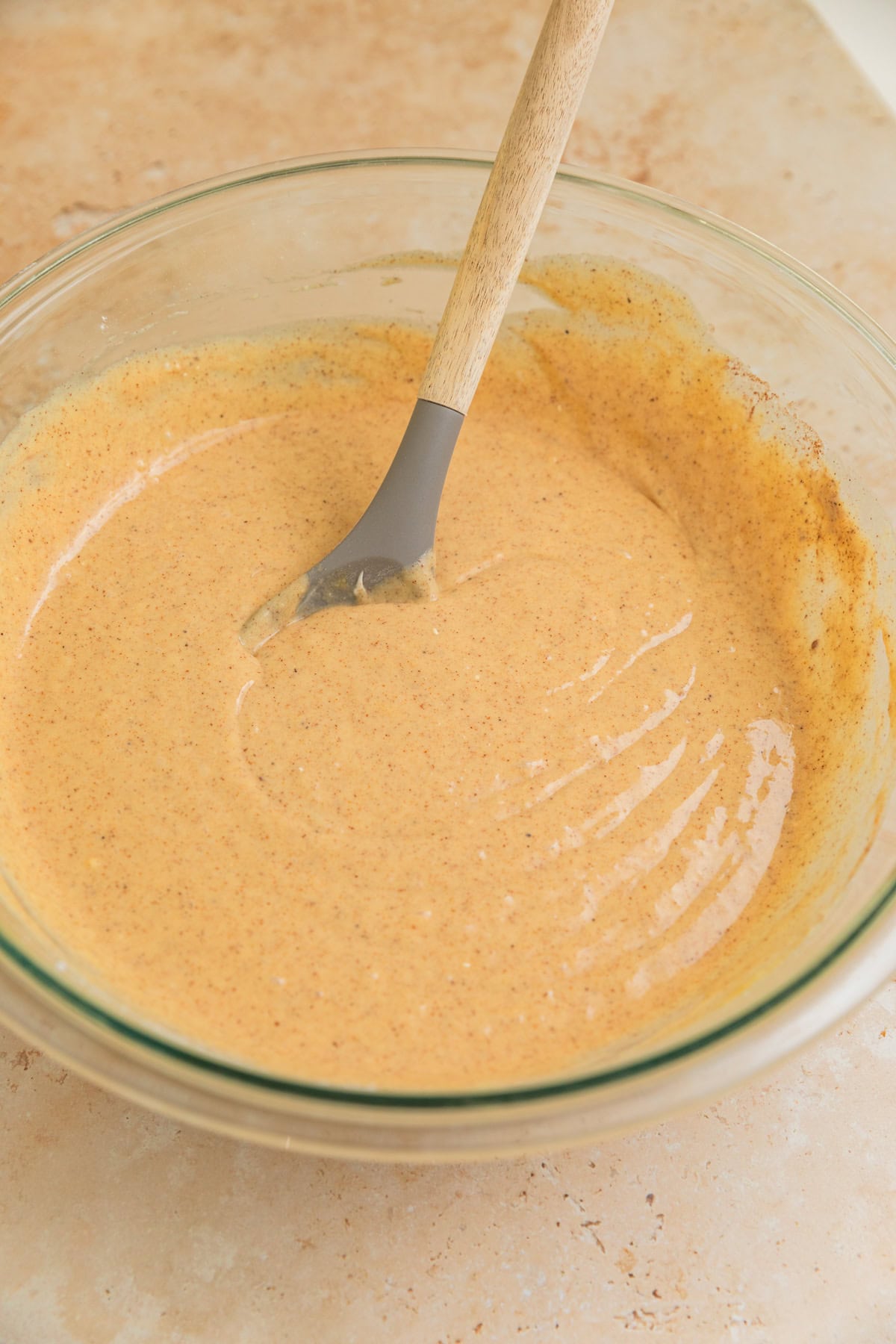 Carrot cake batter mixture in bowl with spoon before adding carrots.