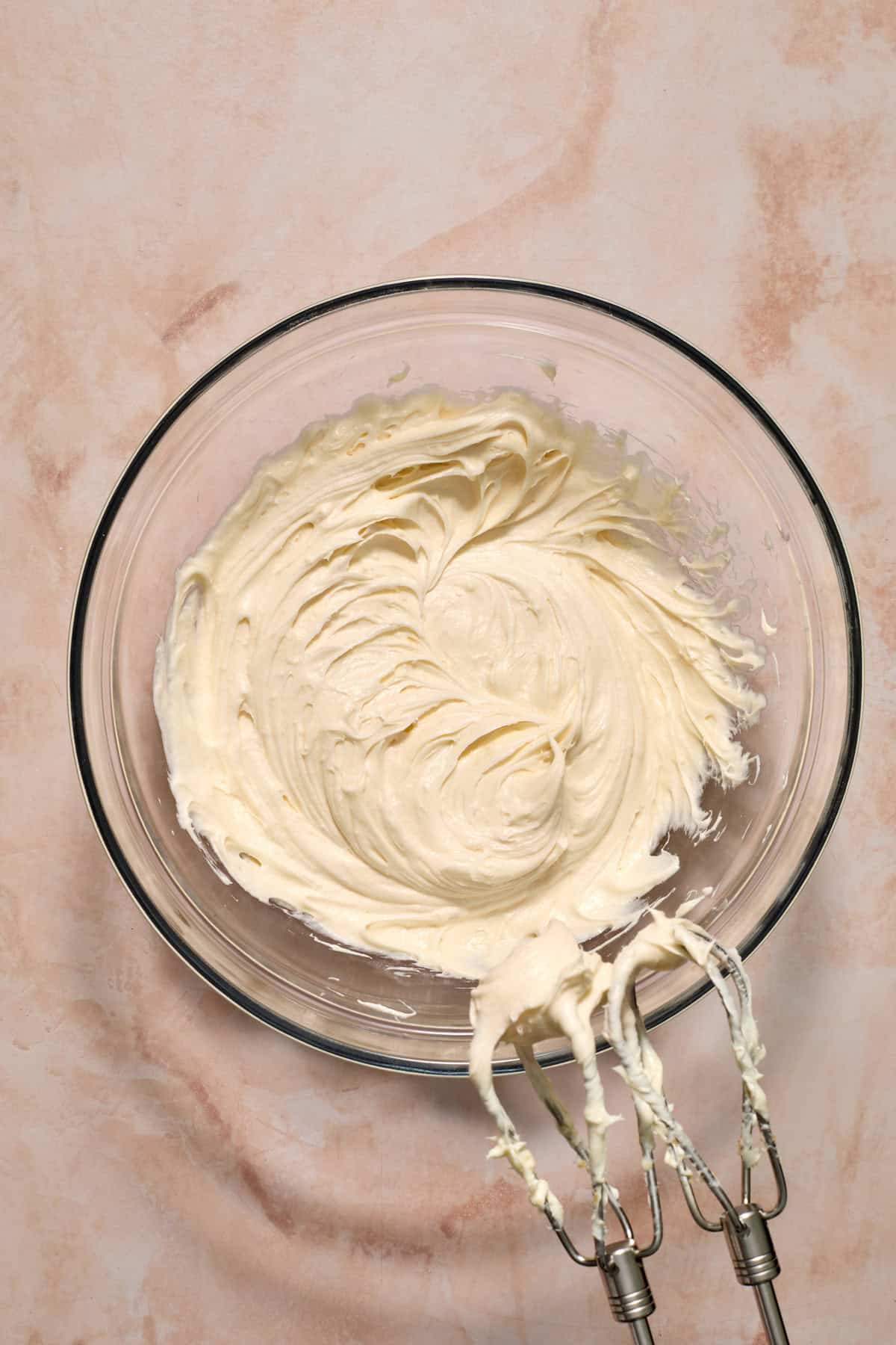 Cream cheese frosting whipped with cream cheese in glass bowl.