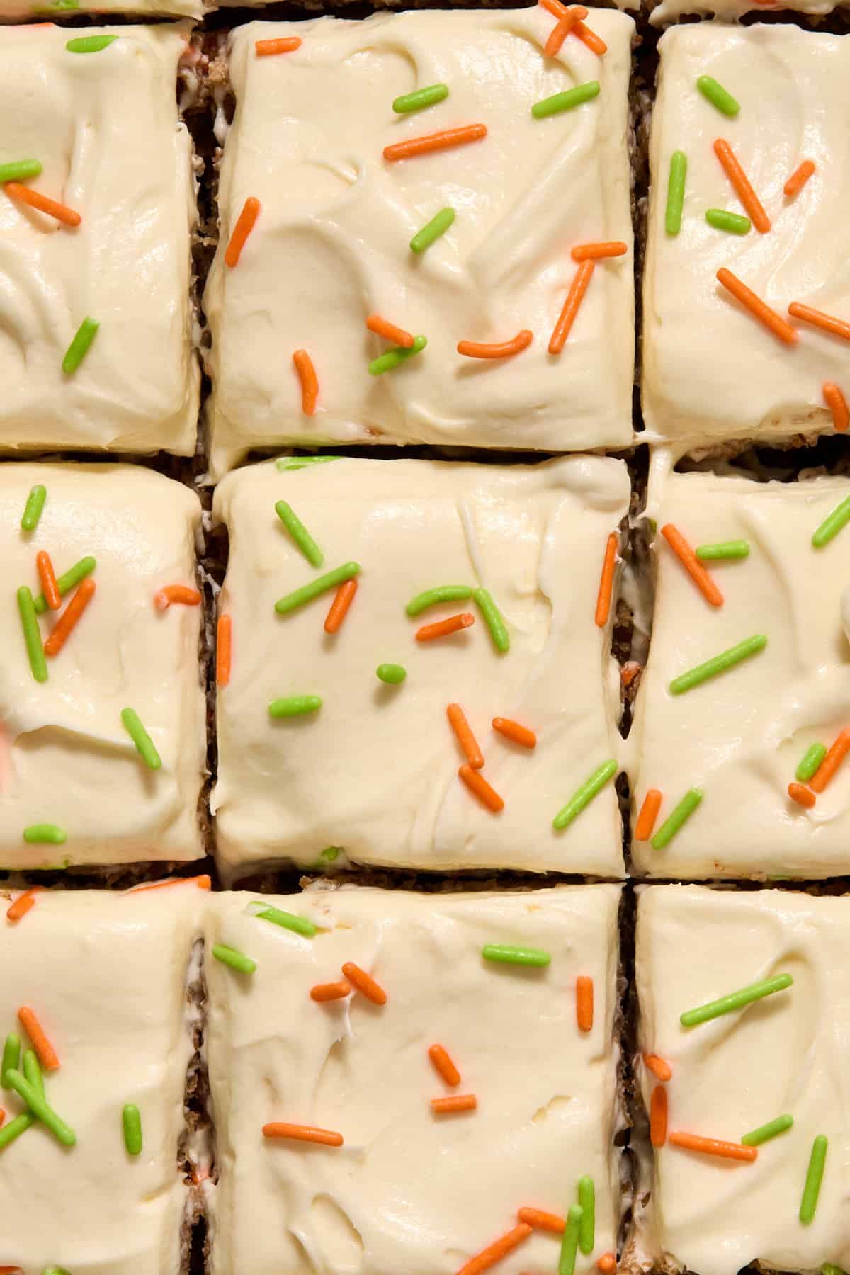 Sliced carrot cake pieces topped with green and orange sprinkles.