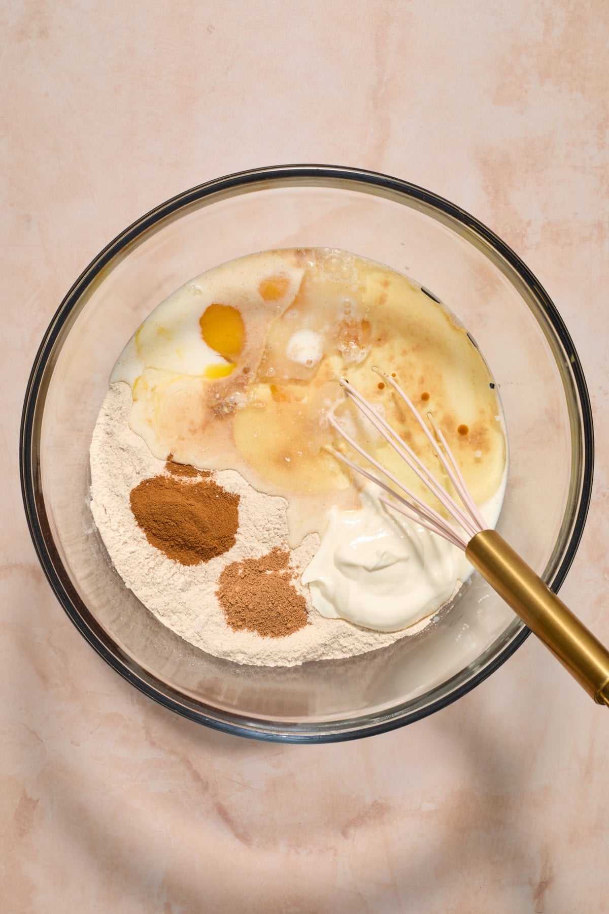 Cake mix, milk, eggs, oil and other ingredients in glass bowl before mixing.