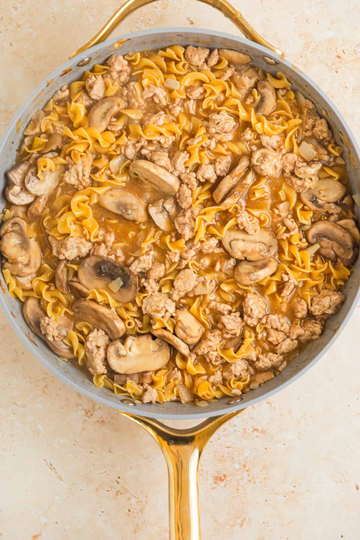Cooked egg noodles in turkey stroganoff cooked in skillet.