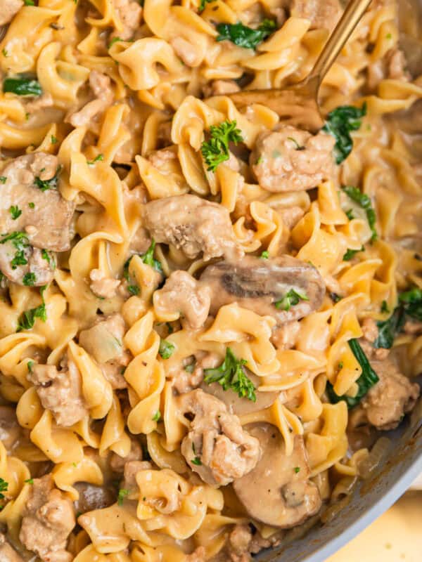 Skillet with ground turkey stroganoff with egg noodles and mushrooms and topped with chopped parsley.