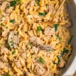 Skillet with ground turkey stroganoff with spoon scooping into the dish.