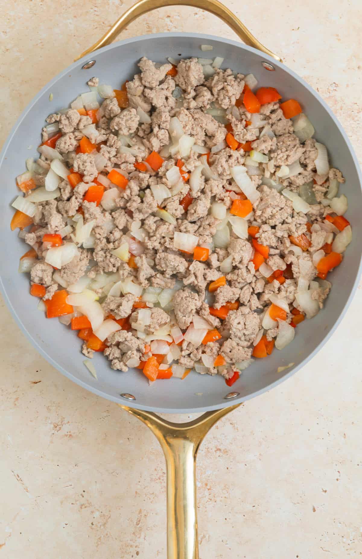 Browned ground turkey with red bell pepper and onion in skillet.