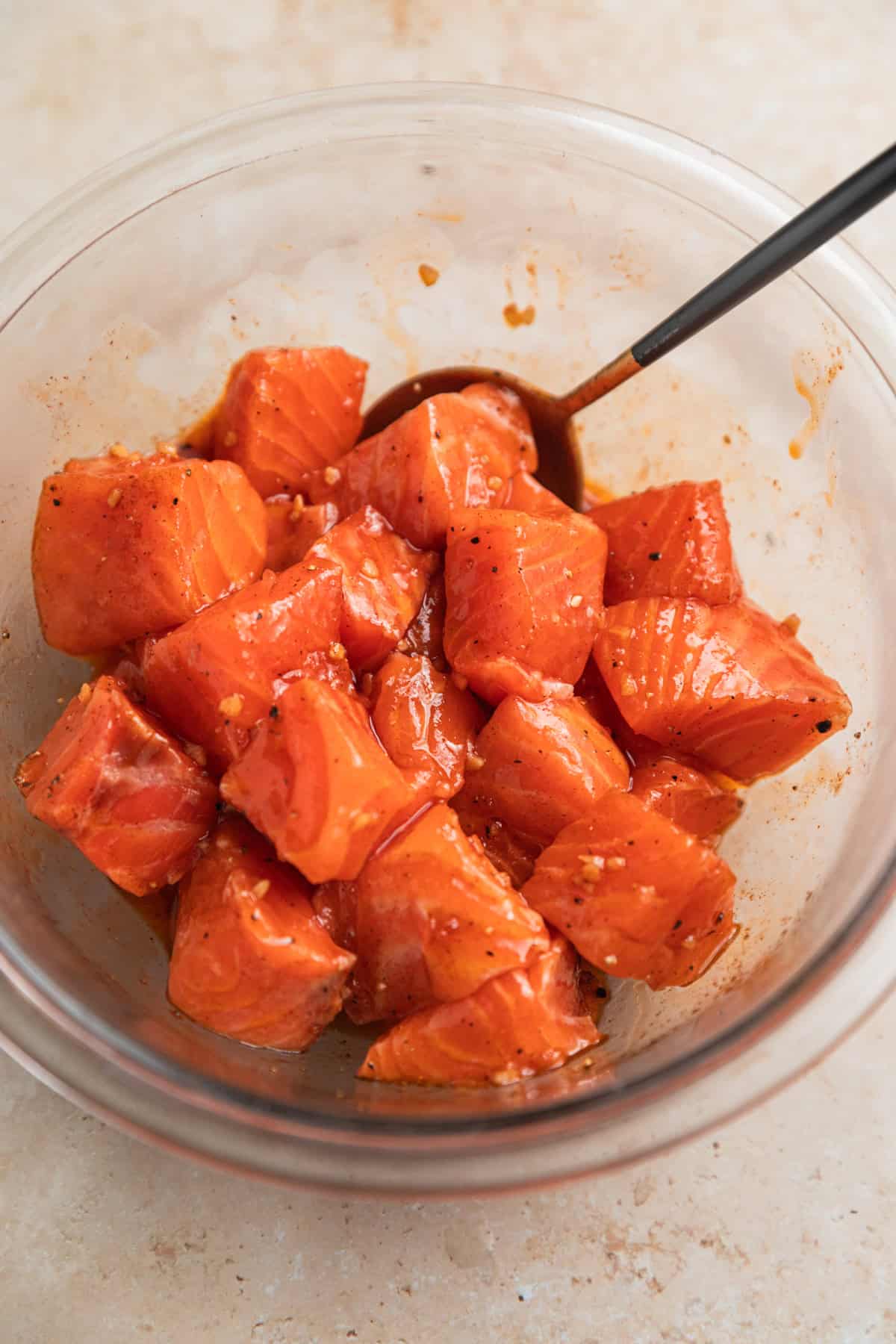 Salmon cubes in glass bowl with marinade.