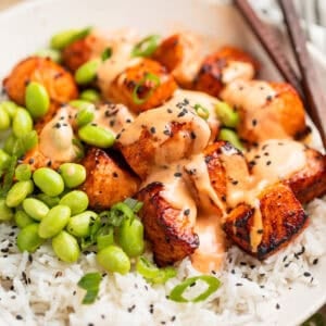 Air fryer salmon bites served with bang bang sauce over top and served on rice.