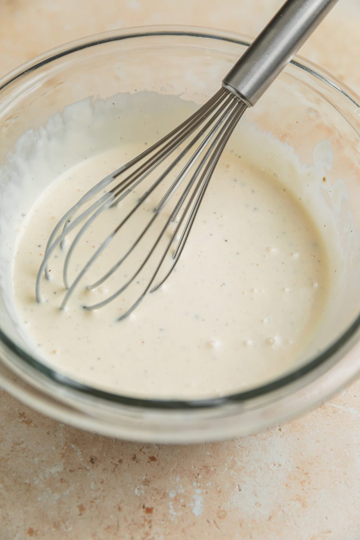 Creamy dressing in bowl with whisk.
