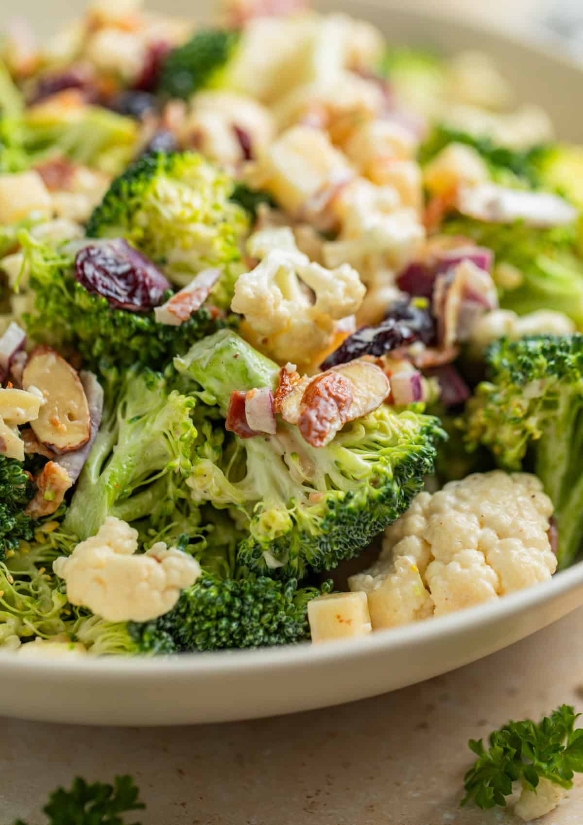 Serving dish with salad topped with chopped bacon, cranberries, almonds and more.