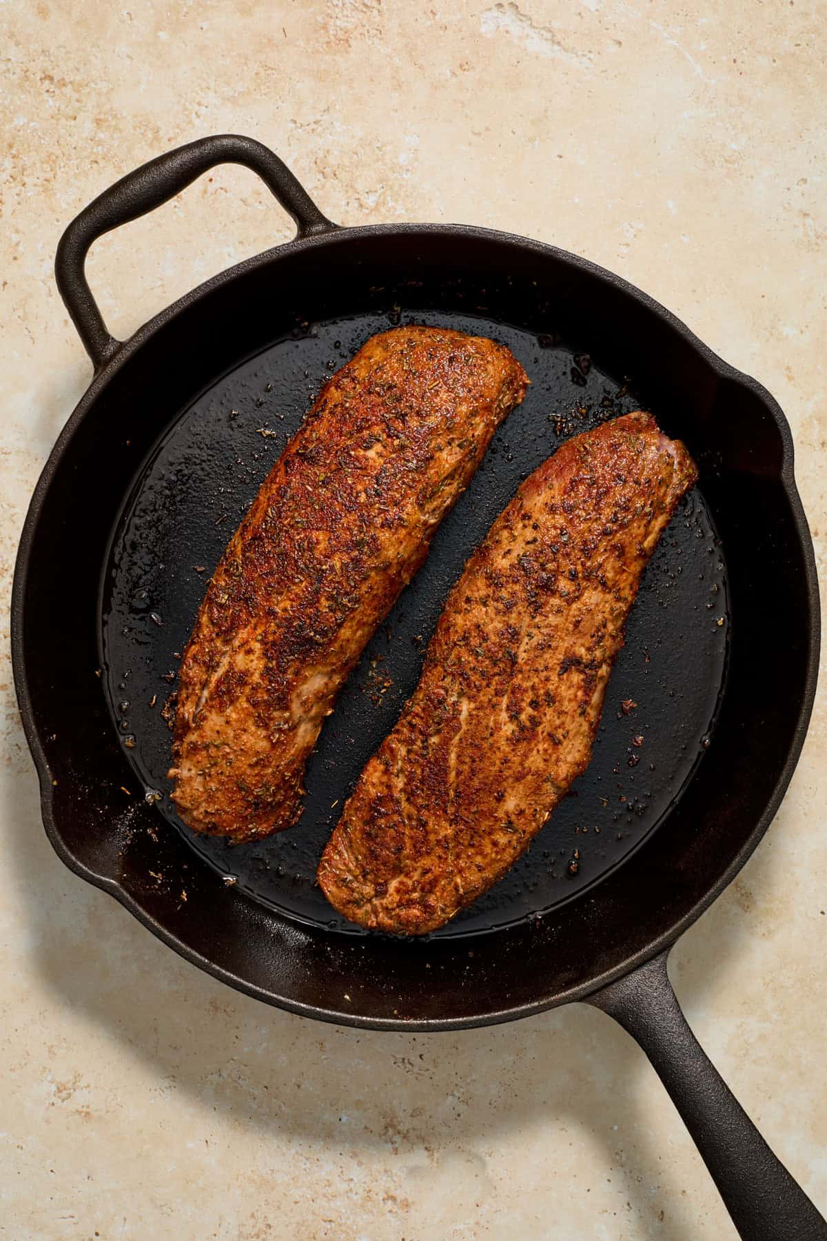 Seared pork tenderloin in skillet.