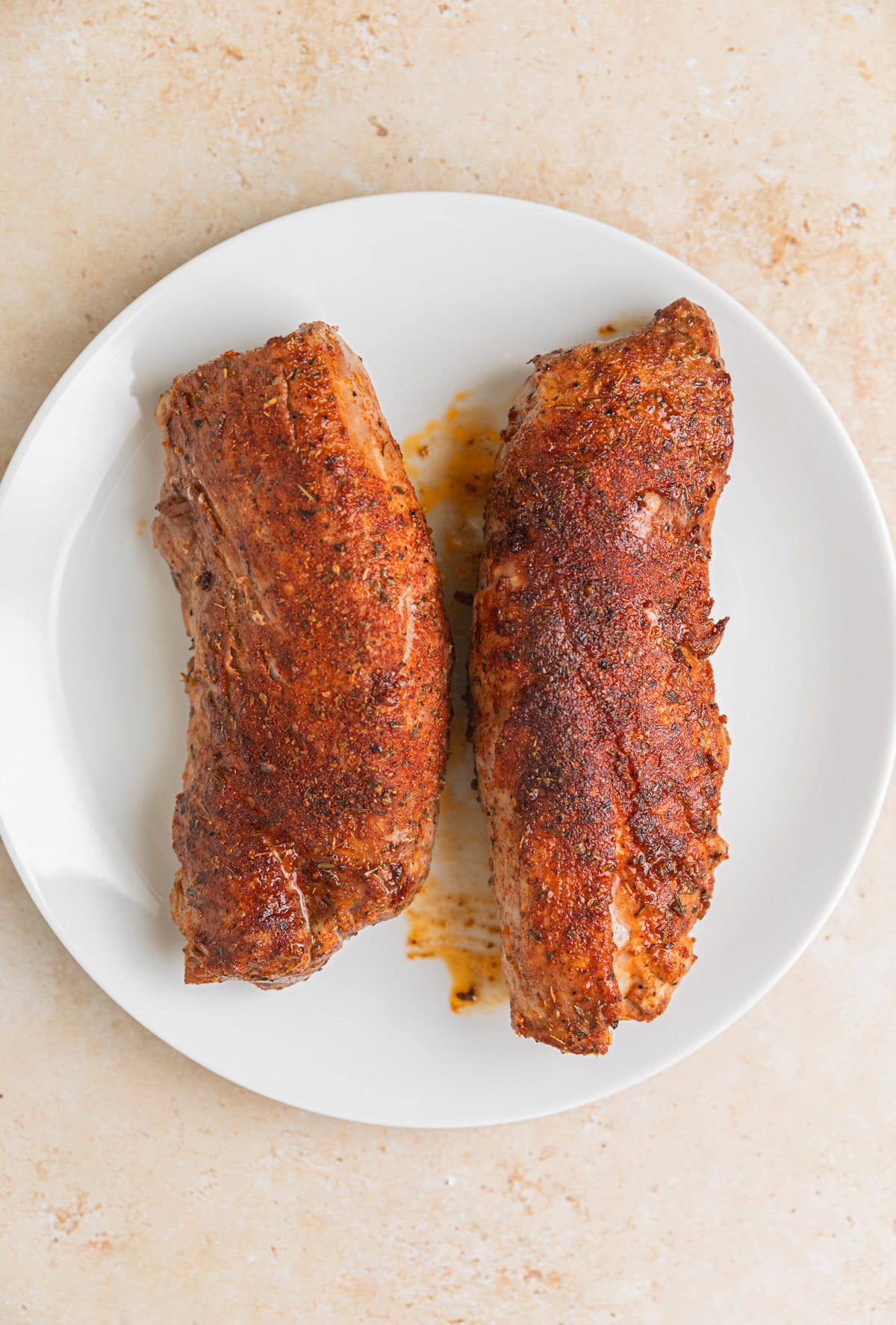 Resting seared pork tenderloin on plate.
