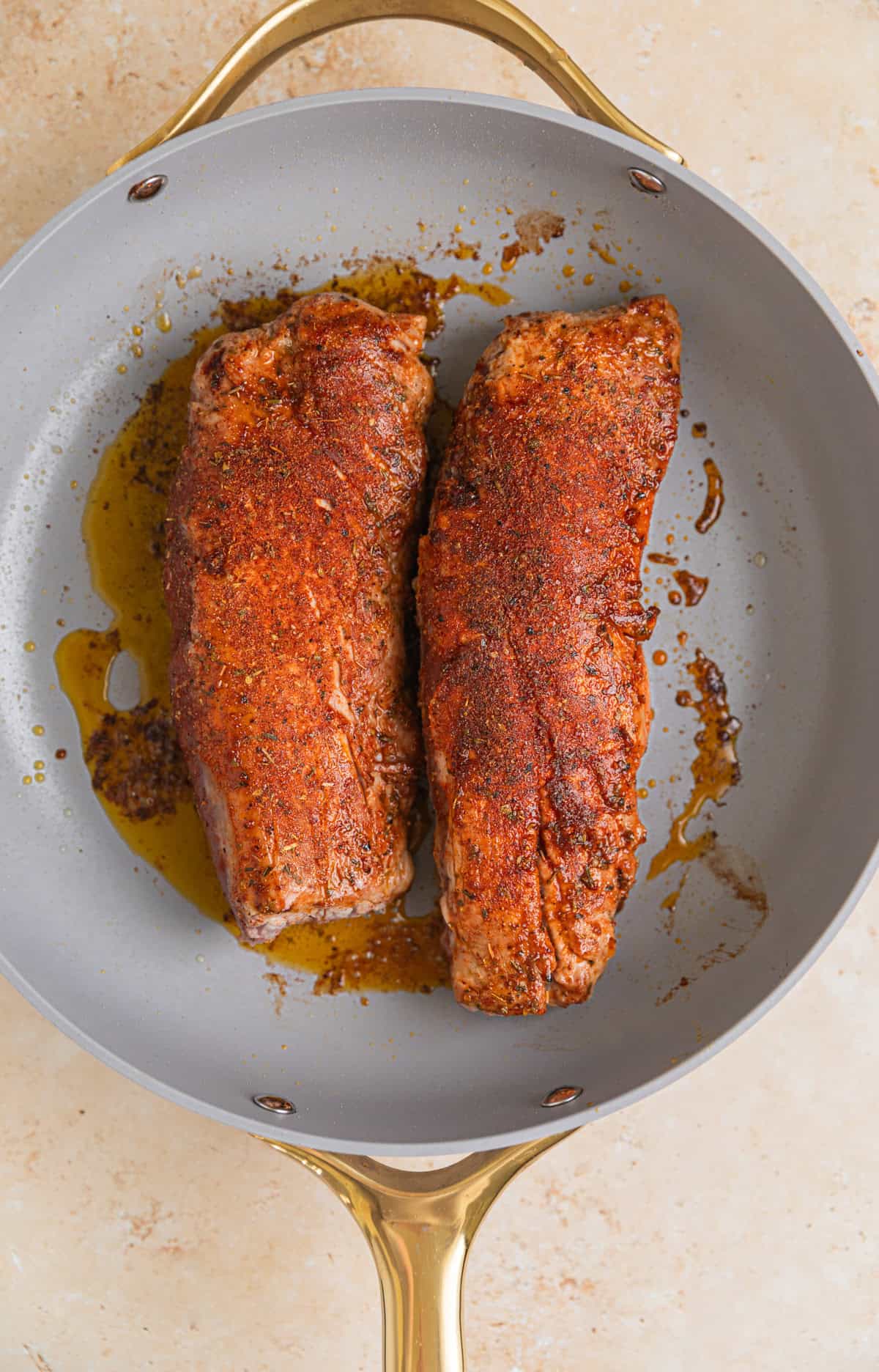 Seared pork tenderloin in skillet.