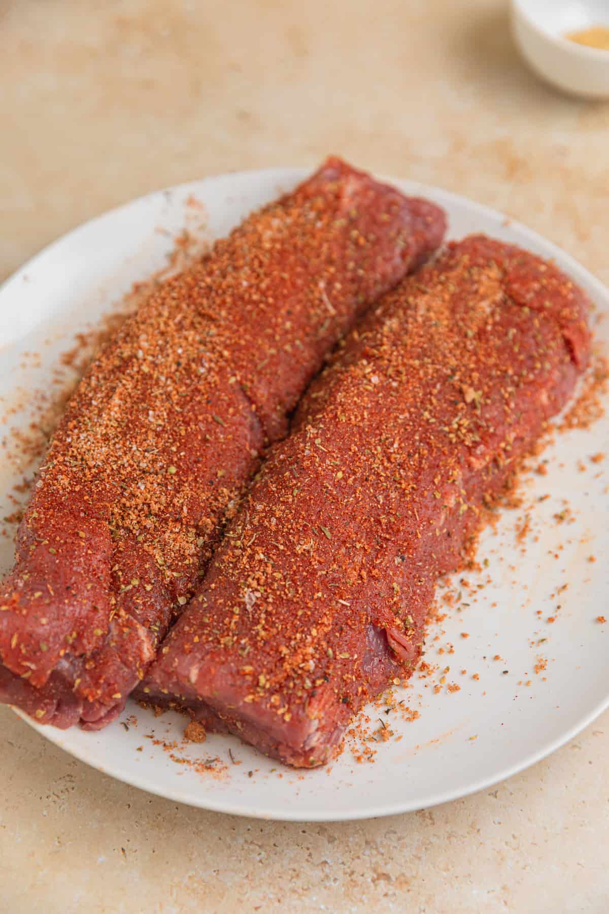 Pork tenderloin on plate with spice rub covering it.