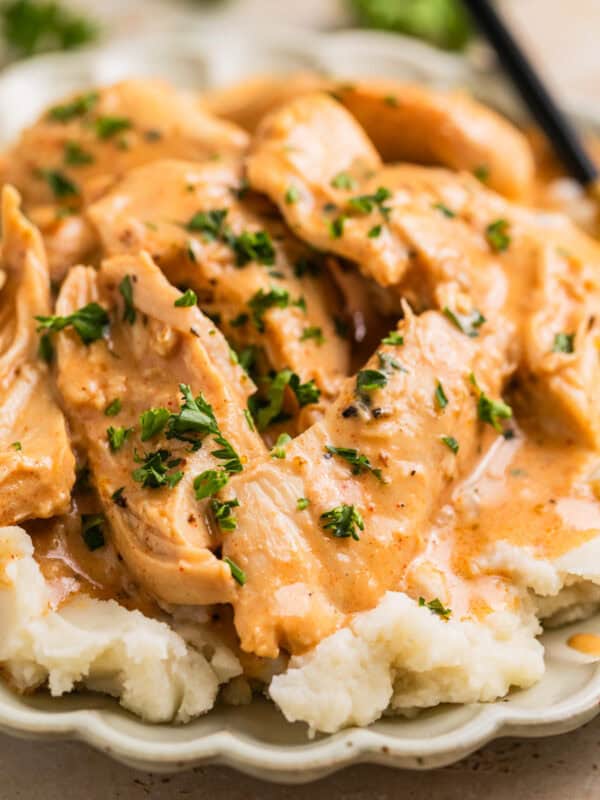Slow cooker honey mustard chicken served over top mashed potatoes.