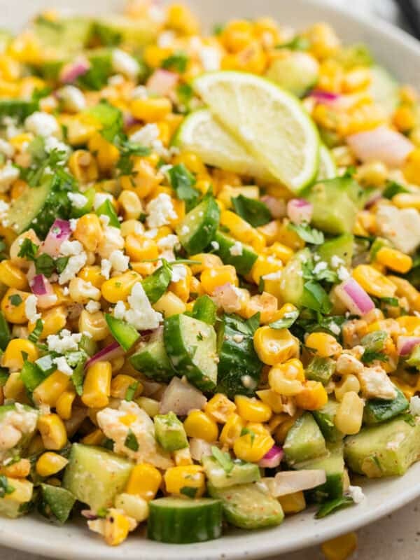 Cucumber corn salad in serving dish topped with chopped jalapeño and cilantro.