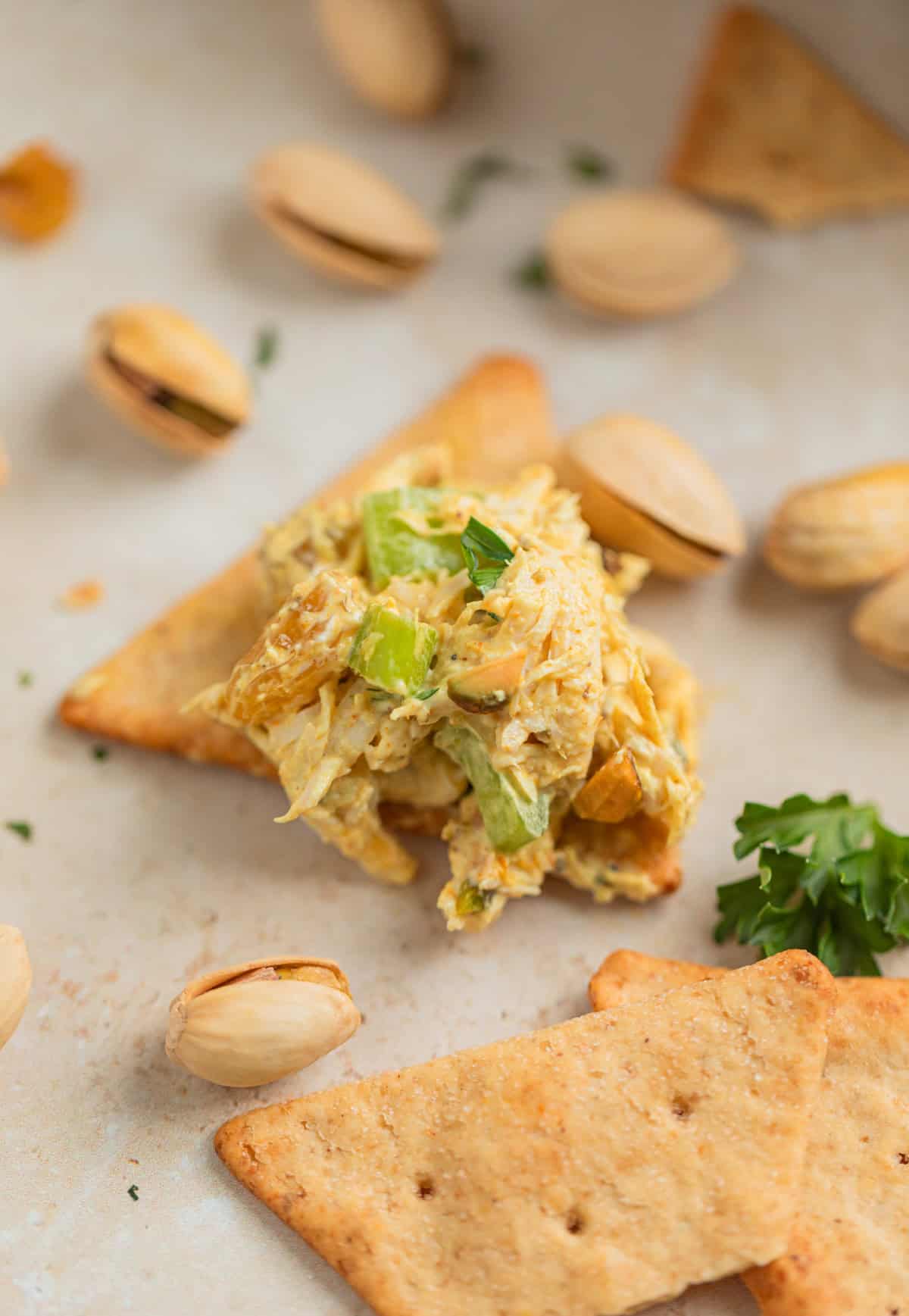 Curry chicken salad served on cracker topped with parsley.