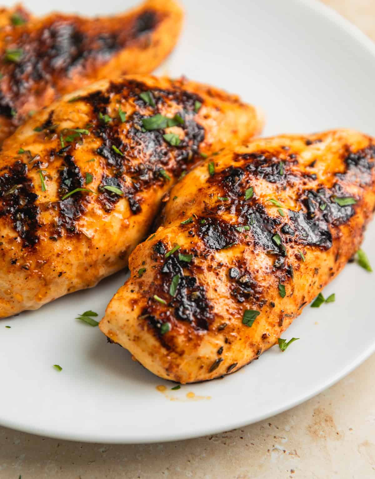 White plate with grilled mediterranean chicken resting.