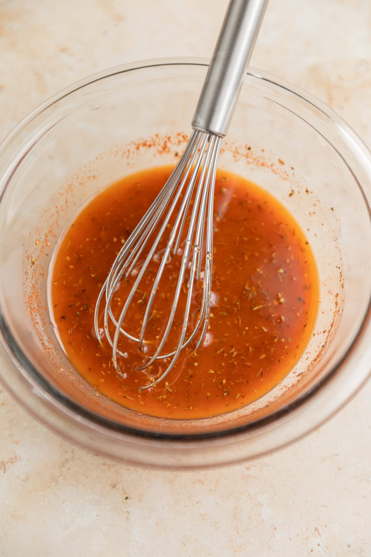 Mediterranean marinade with whisk in glass bowl.
