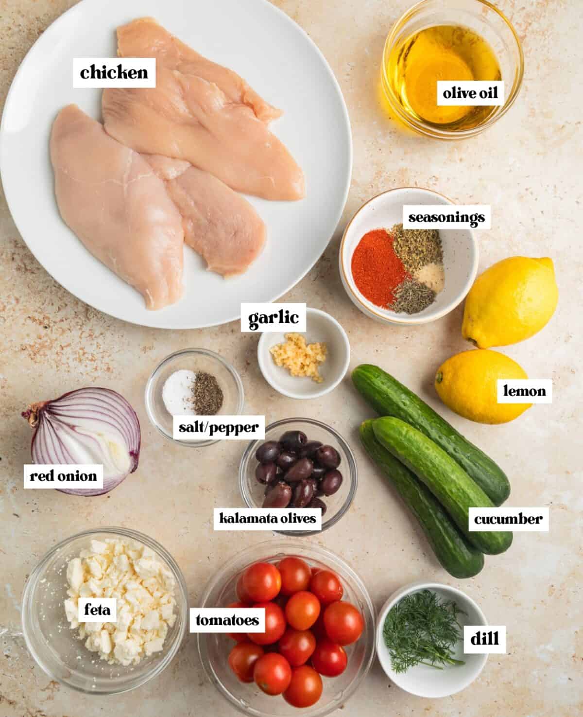 Chicken breast, cucumbers, olive oil, seasonings and other labeled ingredients on surface.