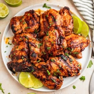 Overhead view of chili lime chicken on white plate with lime slices.