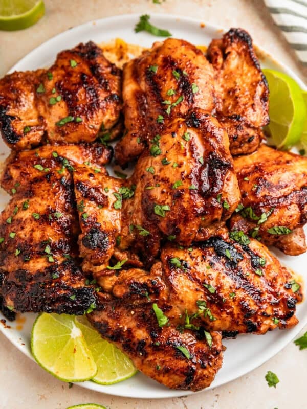 Overhead view of chili lime chicken on white plate with lime slices.
