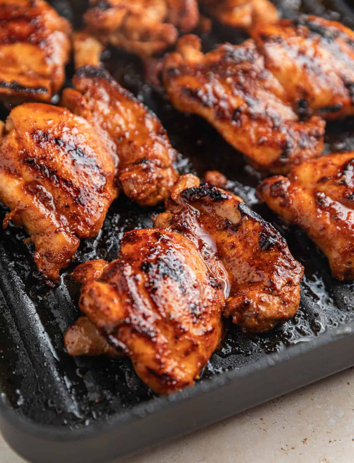 Chicken grilled on grill pan with extra marinade spread over top.
