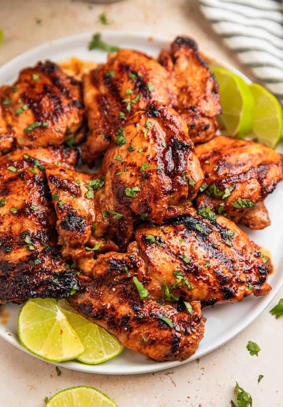 Grilled chili lime marinated chicken thighs on white plate topped with chopped cilantro.