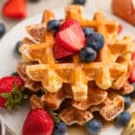 Cottage cheese waffles stacked on plate with berries.