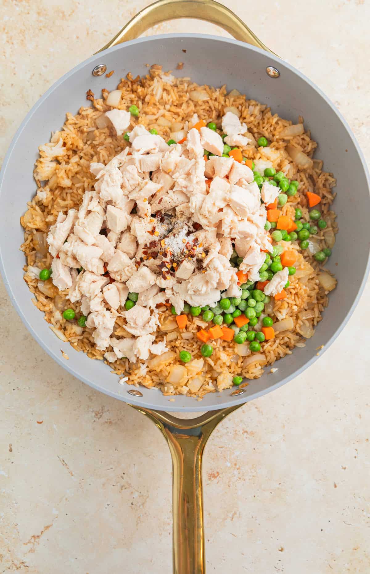 Chicken, frozen peas and carrots and other ingredients added to skillet with fried rice.