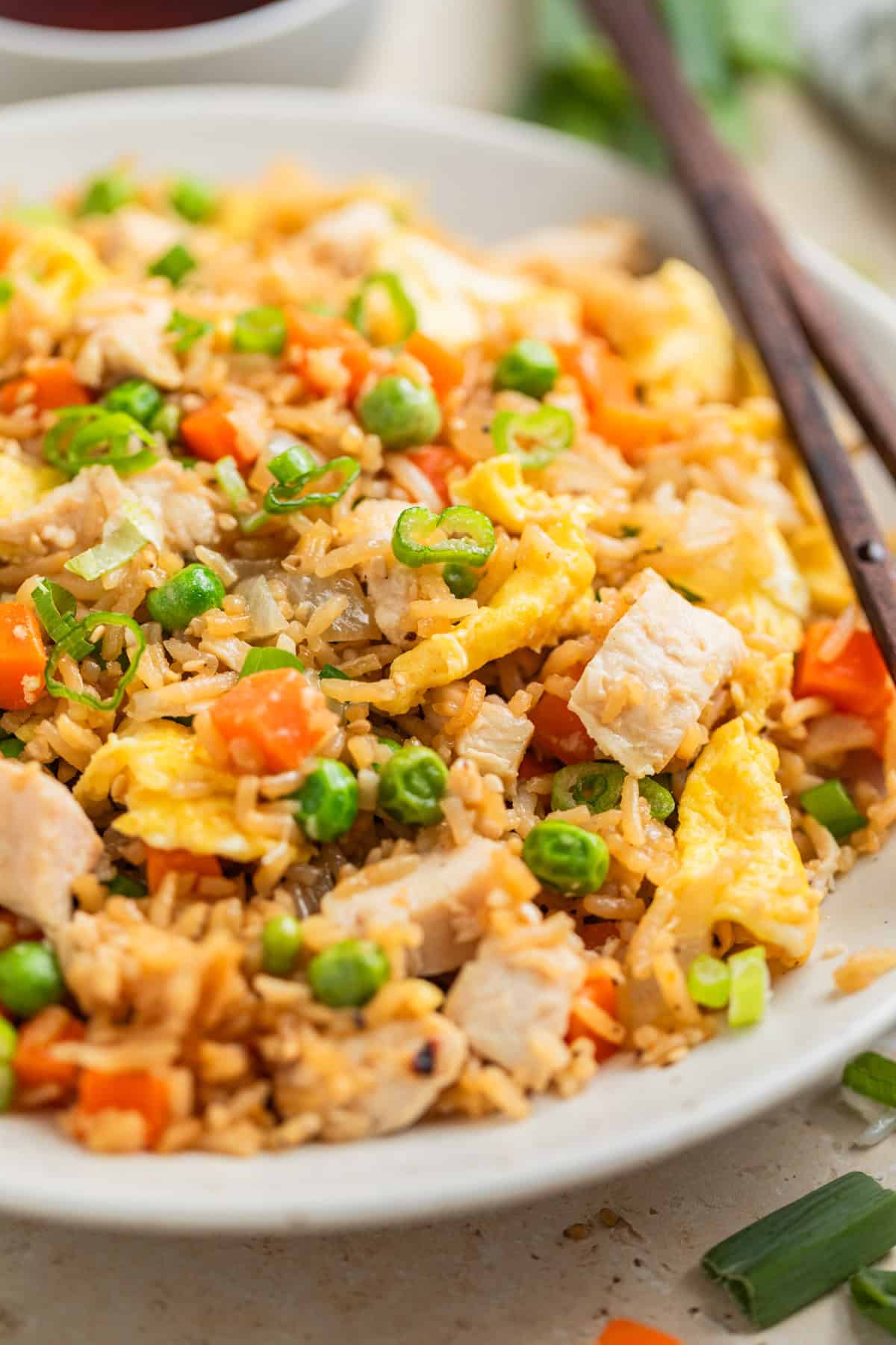 Rotisserie chicken fried rice served on white plate with chopsticks.
