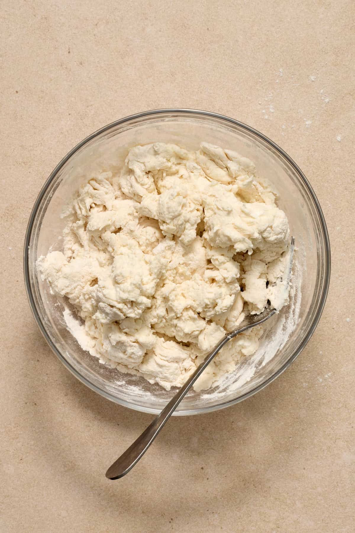 Greek yogurt bagel dough mixture in glass bowl with metal spoon.