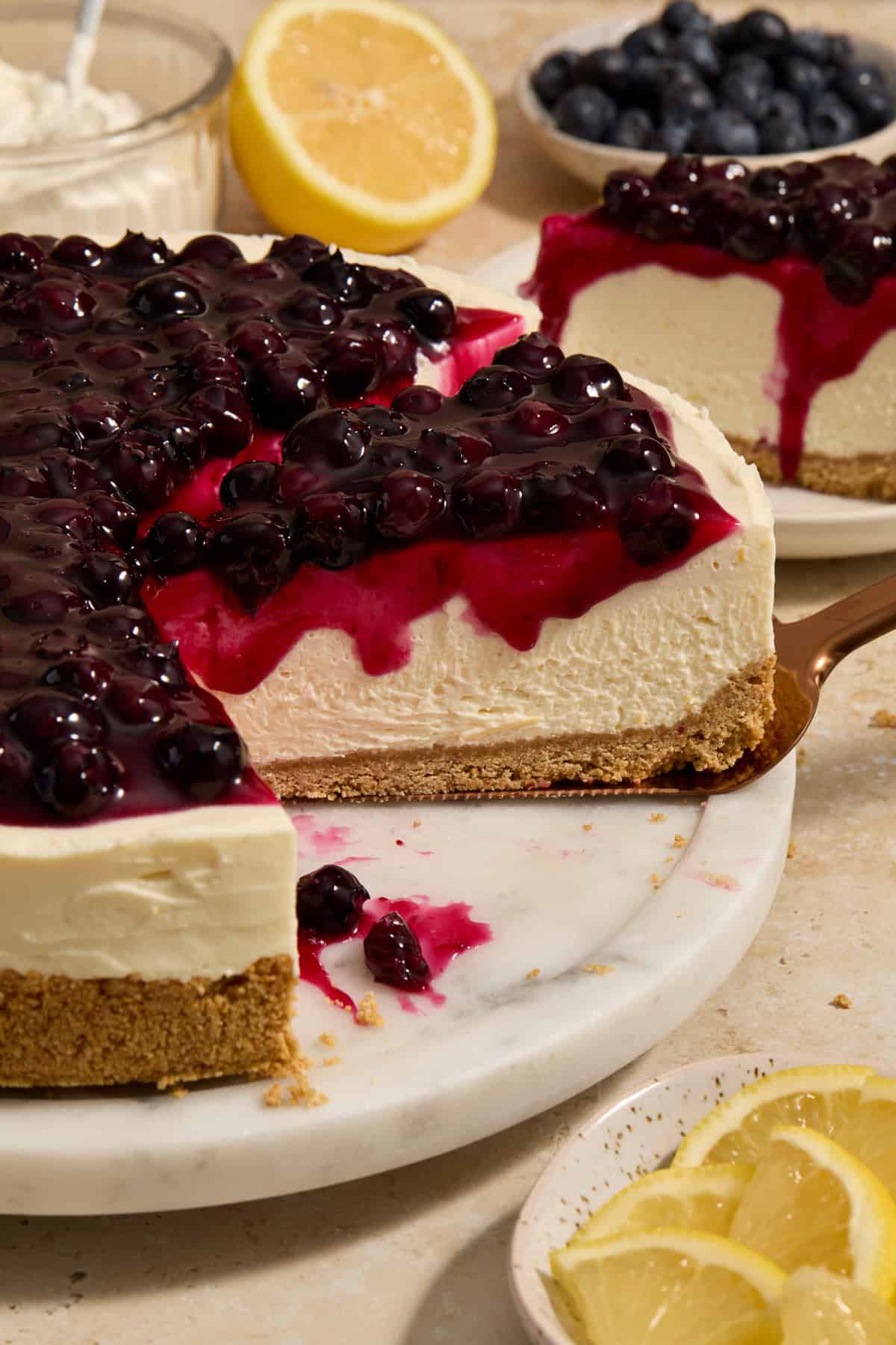 Slice of lemon blueberry no bake cheesecake being pulled on spatula.