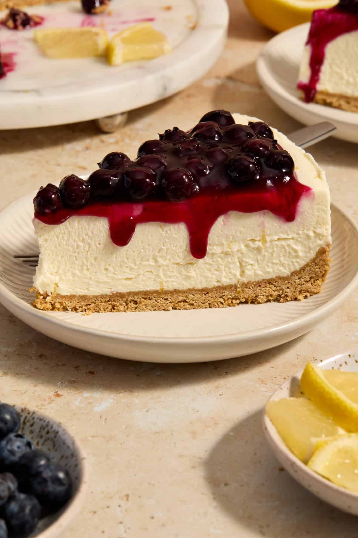 Slice of blueberry lemon cheesecake on plate.
