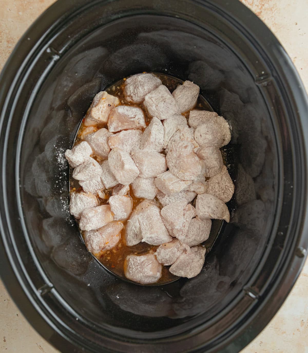 Slow cooker pot with cornstarch coated chicken.