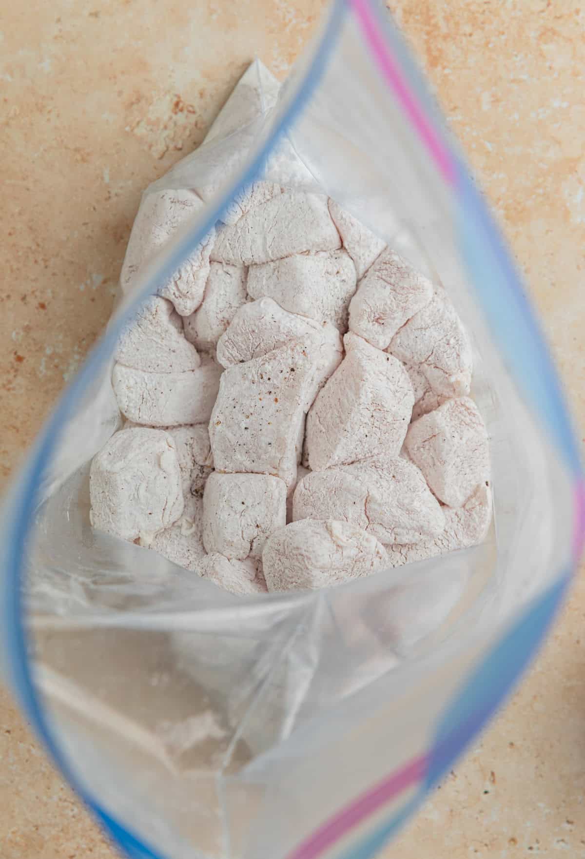 Cornstarch coated chicken breast cubes in plastic bag. 
