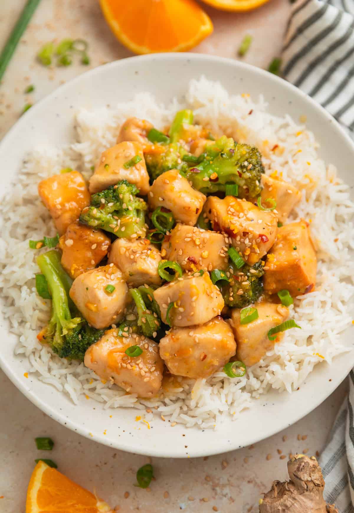 Crockpot orange chicken with broccoli over white rice on plate.