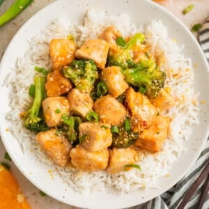 Overhead view of orange chicken on plate of rice with broccoli.