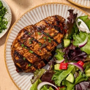 Grilled balsamic chicken breast served on plate topped with chopped parsley.