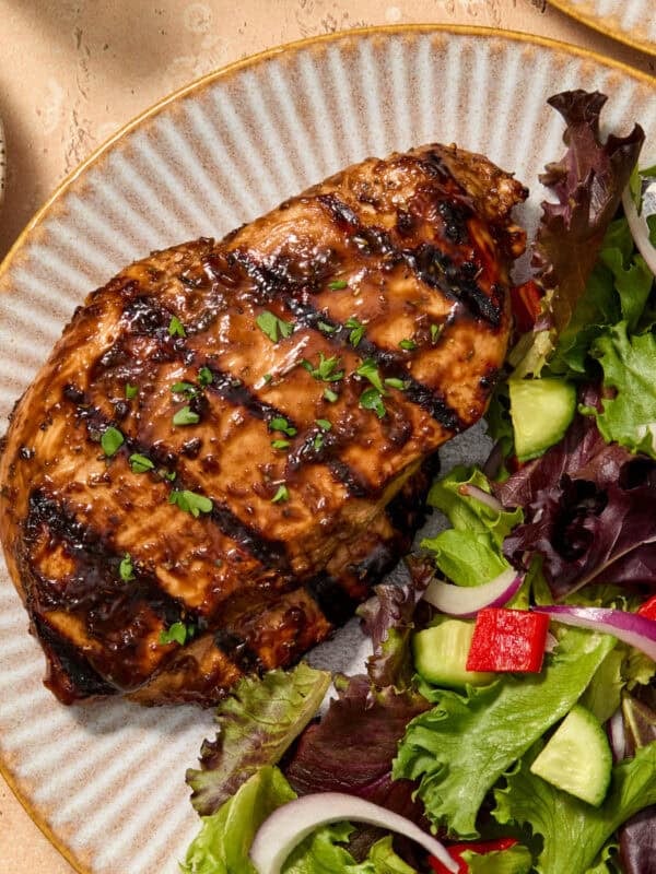 Grilled balsamic chicken breast served on plate topped with chopped parsley.