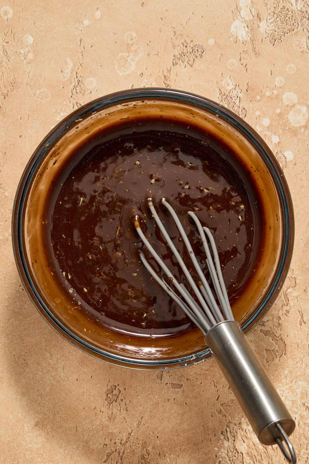 Balsamic marinade in glass bowl with whisk.