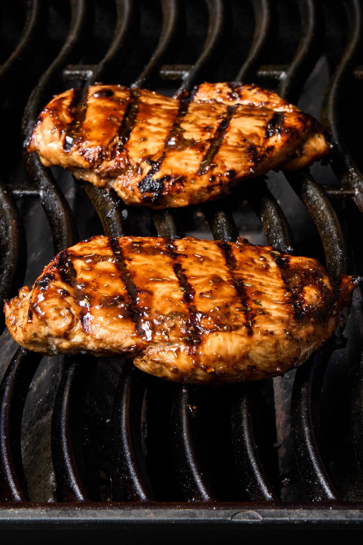 Chicken on grill with marinade brushed over top.