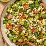 Salad with grilled corn, romaine, avocado, tomato in bowl.