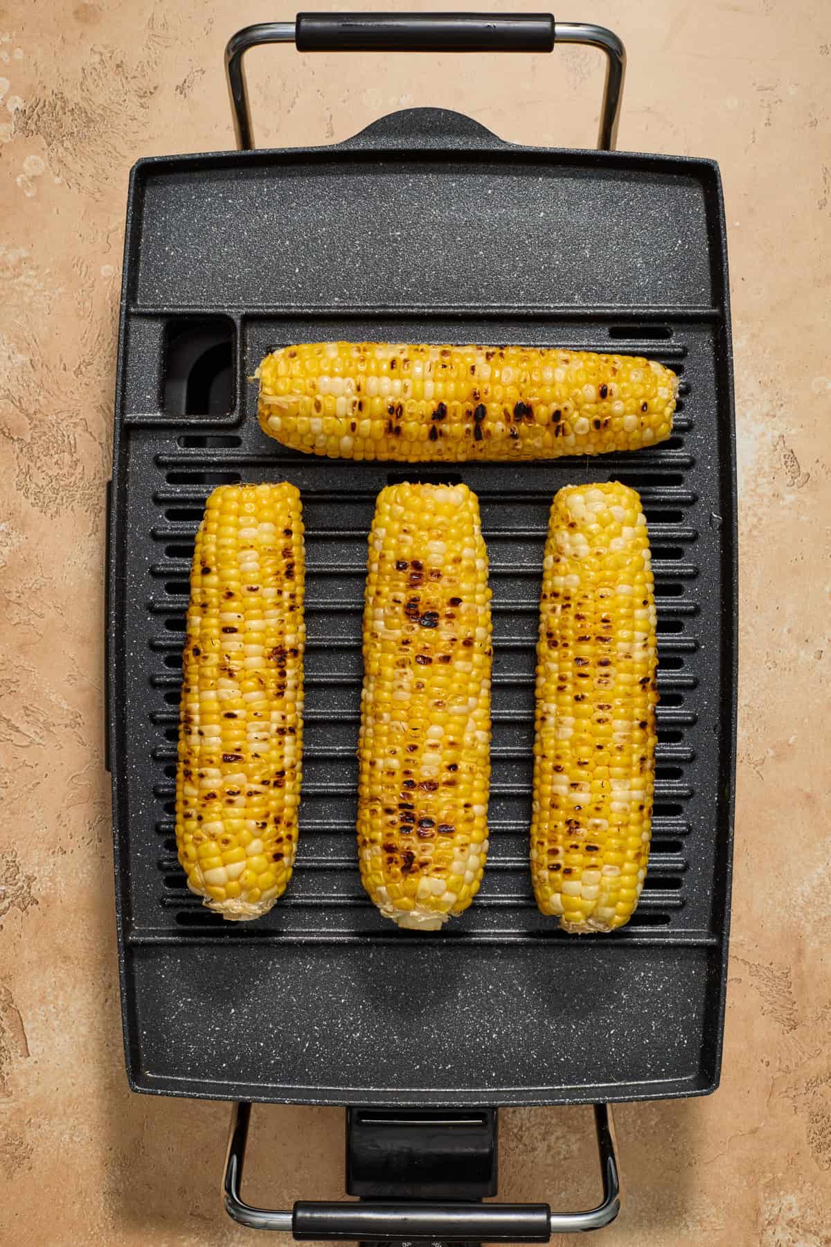 Corn being grilled on grill appliance.