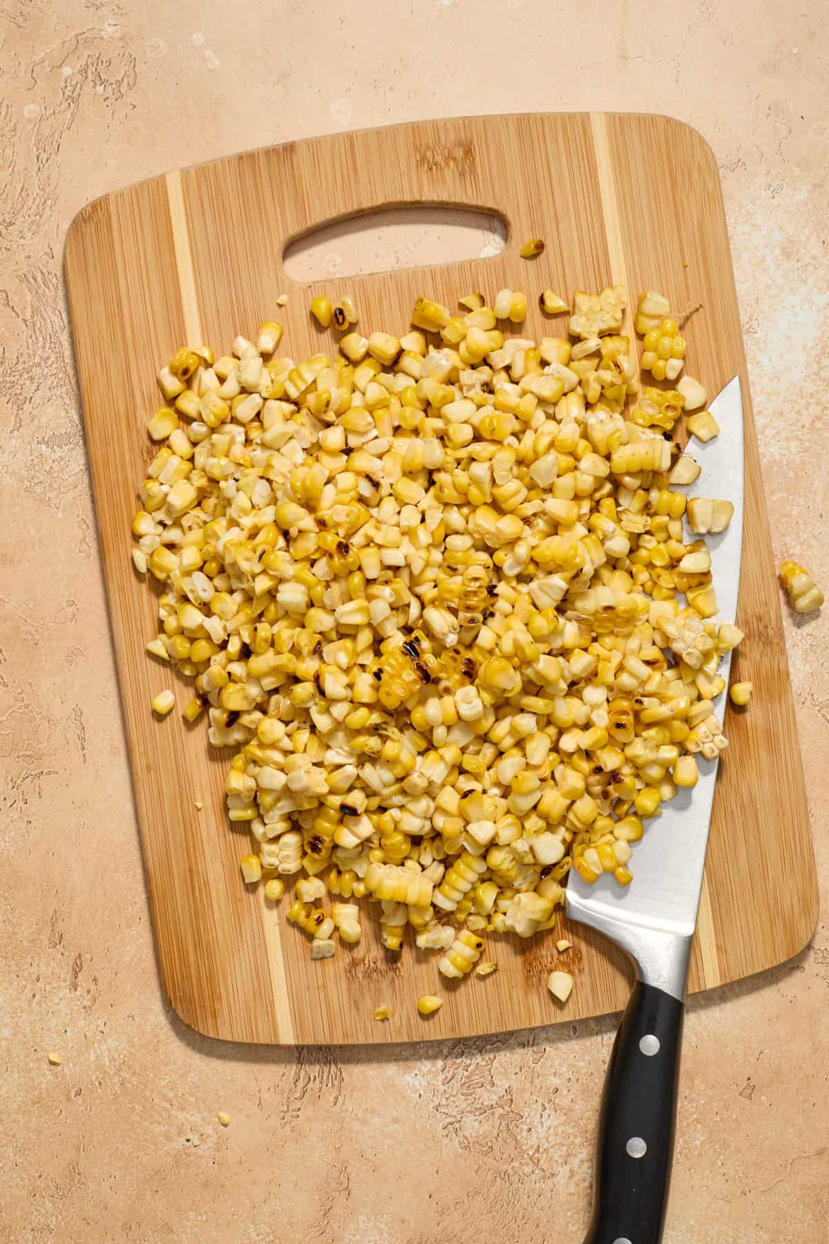 Grilled corn cut from the cob on cutting board.