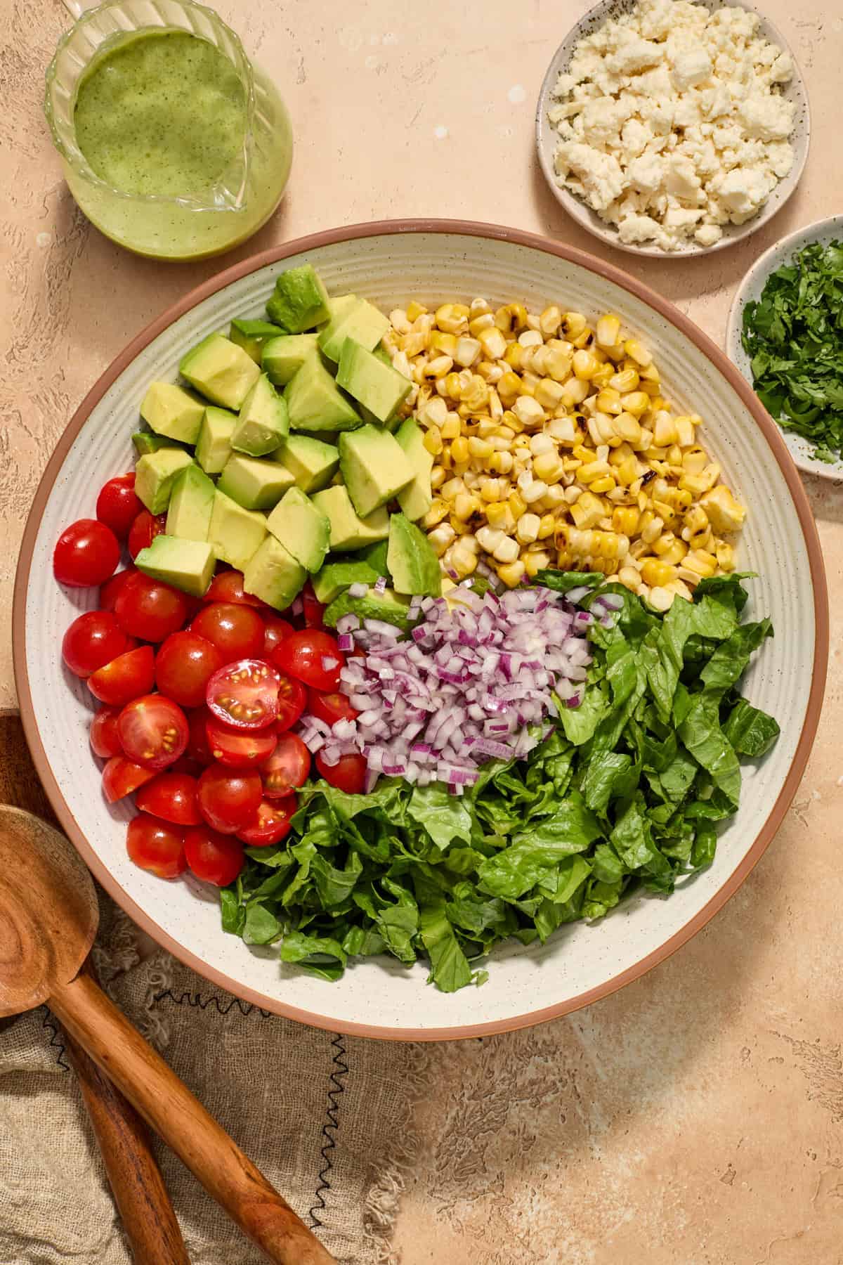 Grilled corn, chopped avocado, tomatoes and other ingredients arranged in salad bowl.
